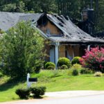 Fire-damaged home exterior after a house fire, showing roof damage and the need for restoration services.