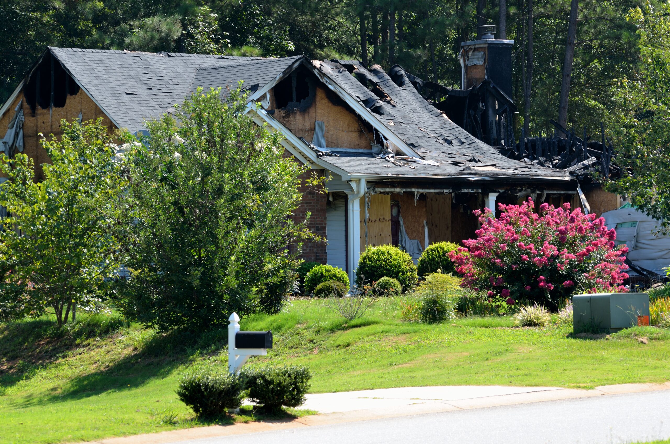 Fire-damaged home exterior after a house fire, showing roof damage and the need for restoration services.